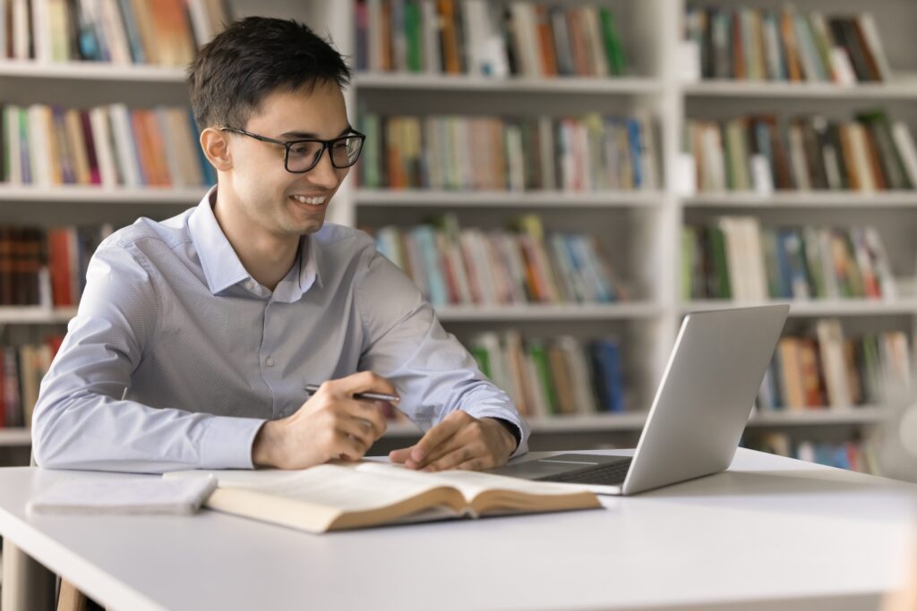 Distant,Schooling.,Smiling,Young,Man,Use,Notebook,At,Library,For